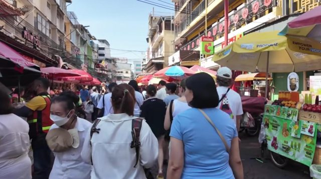 Wisatawan perempuan solo sedang berfoto di depan bangunan bersejarah Thailand
