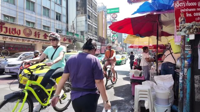 Wisatawan bersepeda di jalur alternatif yang tenang dan asri di Bangkok.