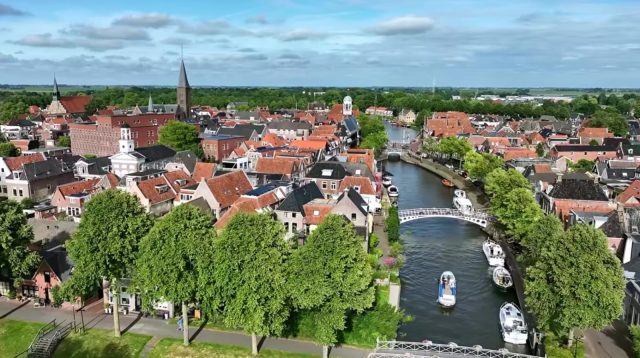 Perahu melintasi kanal di tengah pemukiman kuno kota Brielle