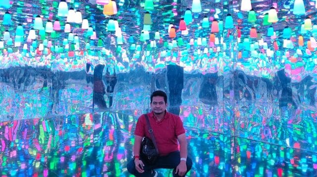 Seorang pria duduk di ruangan terapi cahaya indoor yang dipenuhi lampu warna-warni untuk efek relaksasi