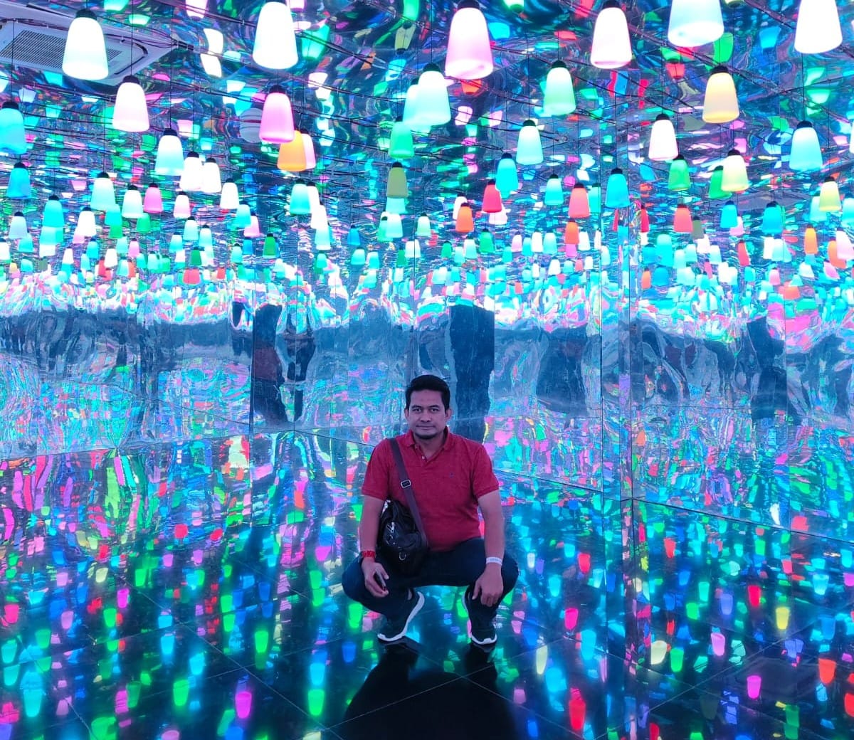 Seorang pria duduk di ruangan terapi cahaya indoor yang dipenuhi lampu warna-warni untuk efek relaksasi
