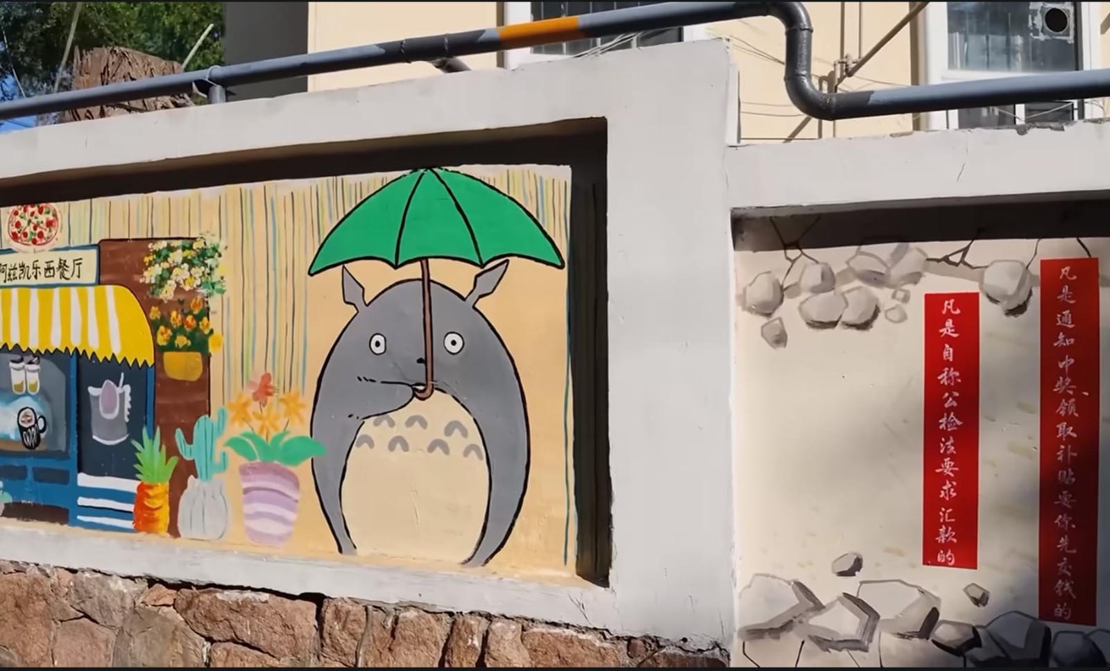 Lukisan mural karakter animasi Totoro memegang payung hijau di tembok jalanan Qingdao