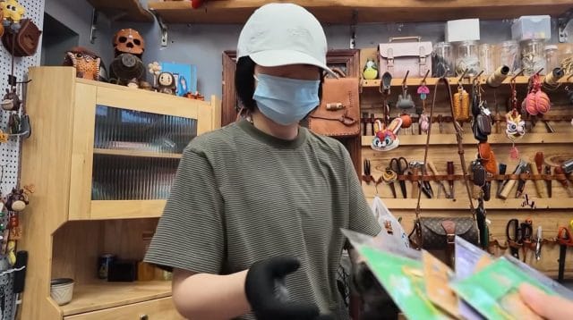 Wirausaha perempuan Qingdao memakai topi dan masker sedang melayani transaksi pelanggan