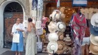 Dua turis perempuan mancanegara sedang melihat-lihat topi dan suvenir di depan butik bergaya modern di Armenian Street Penang