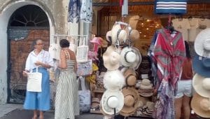Dua turis perempuan mancanegara sedang melihat-lihat topi dan suvenir di depan butik bergaya modern di Armenian Street Penang