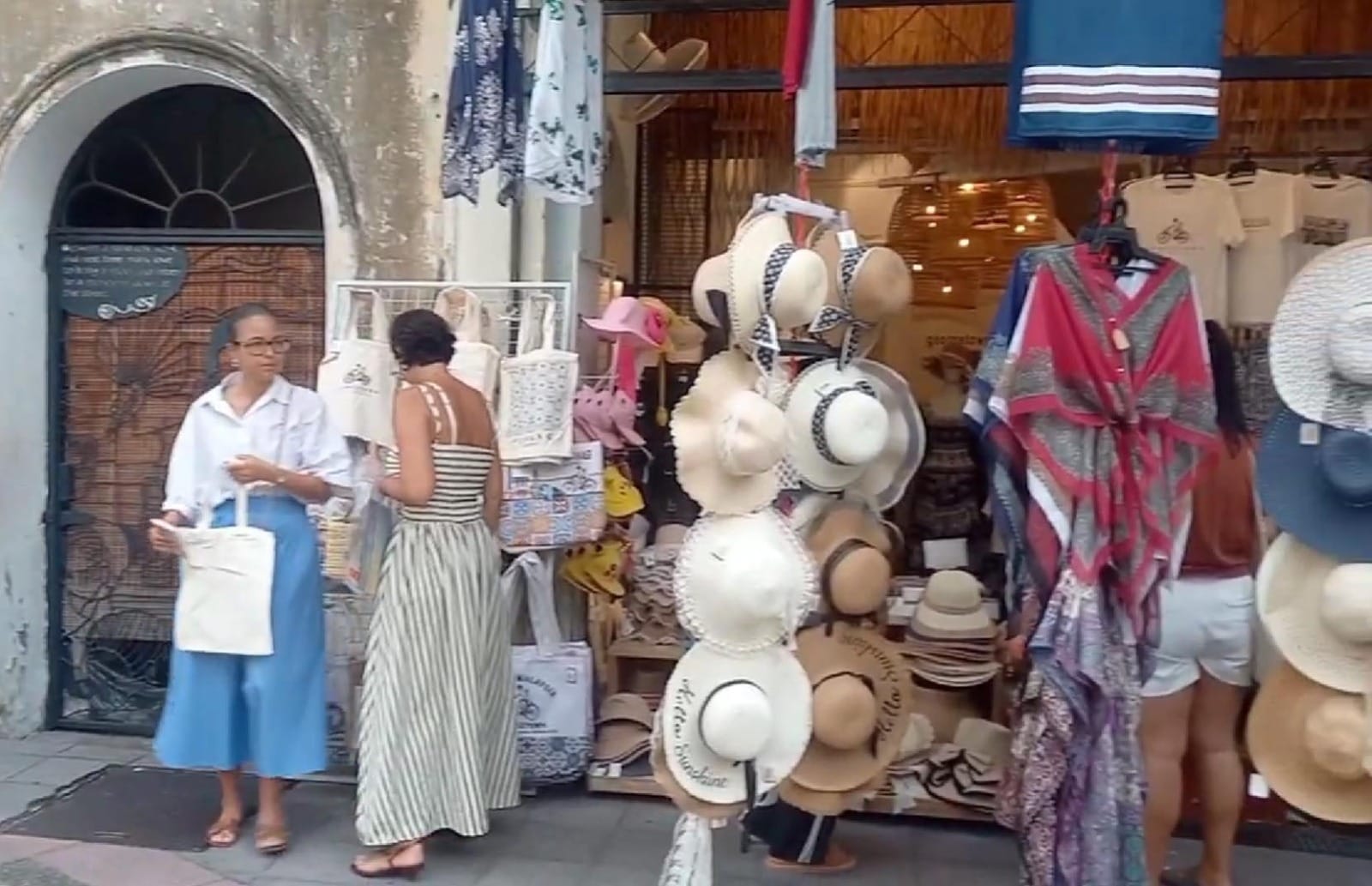 turis-perempuan-berbelanja-di-penang Dua turis perempuan mancanegara sedang melihat-lihat topi dan suvenir di depan butik bergaya modern di Armenian Street Penang