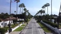 Trotoar lebar dan asri di kawasan perumahan ramah pejalan kaki yang dipenuhi warga beraktivitas.