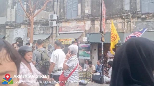 Seorang turis mancanegara berjalan kaki melewati dekorasi durian raksasa di trotoar Armenian Street