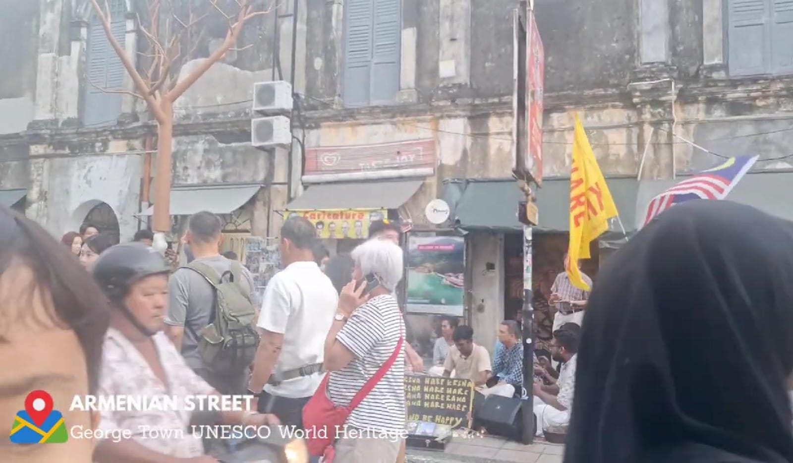 Seorang turis mancanegara berjalan kaki melewati dekorasi durian raksasa di trotoar Armenian Street