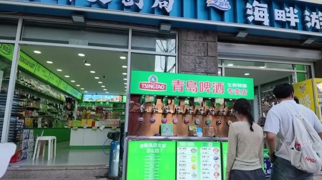 Toko suvenir resmi bir Tsingtao dengan papan pengumuman hijau mencolok di depan pintu masuk