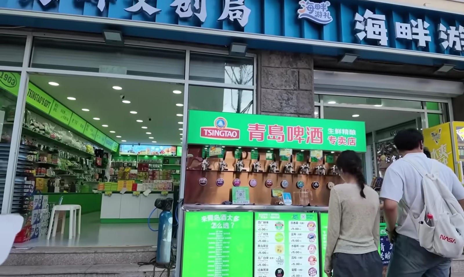 Toko suvenir resmi bir Tsingtao dengan papan pengumuman hijau mencolok di depan pintu masuk