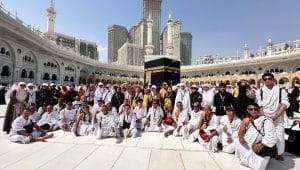 Rombongan jamaah umroh asal Indonesia berfoto bersama dengan latar belakang Ka'bah setelah melaksanakan umroh wada