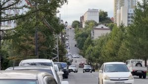 Arus kendaraan dan pejalan kaki di jalanan kota Khabarovsk yang tertib dengan latar perpaduan arsitektur klasik dan modern.