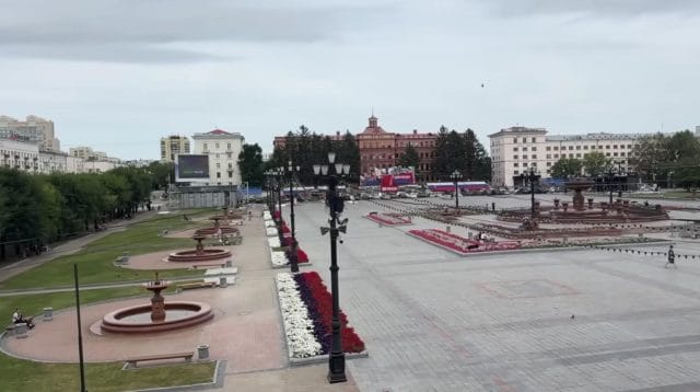 Pemandangan alun-alun dan ruang terbuka di Khabarovsk yang luas dengan air mancur dan taman bunga yang tertata estetik.