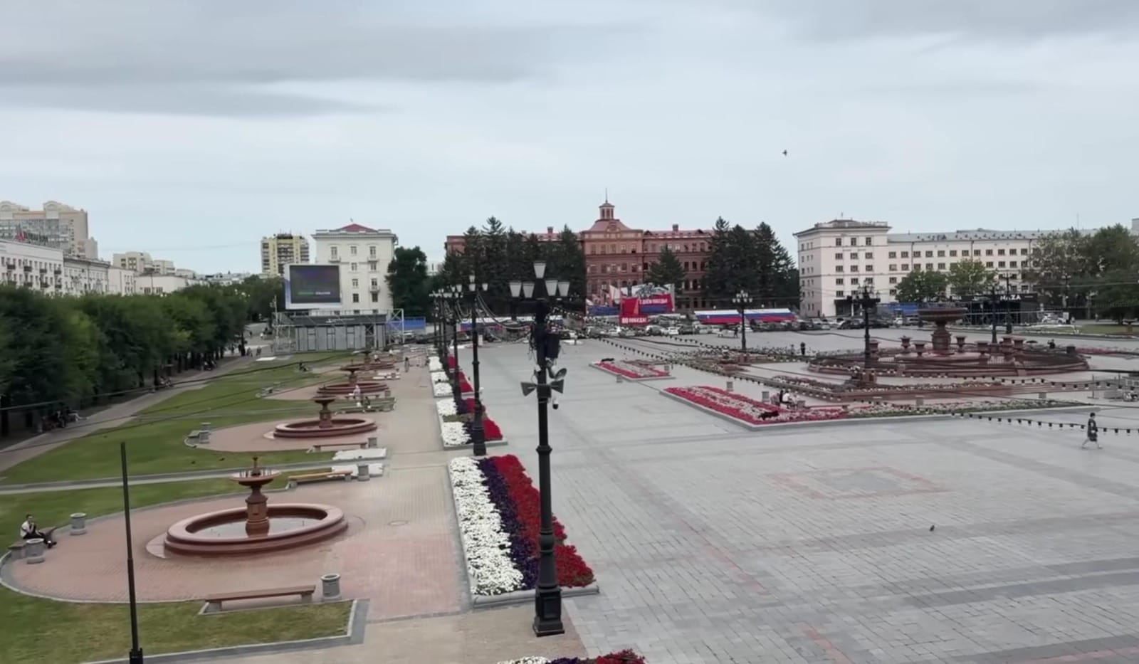 Pemandangan alun-alun dan ruang terbuka di Khabarovsk yang luas dengan air mancur dan taman bunga yang tertata estetik.