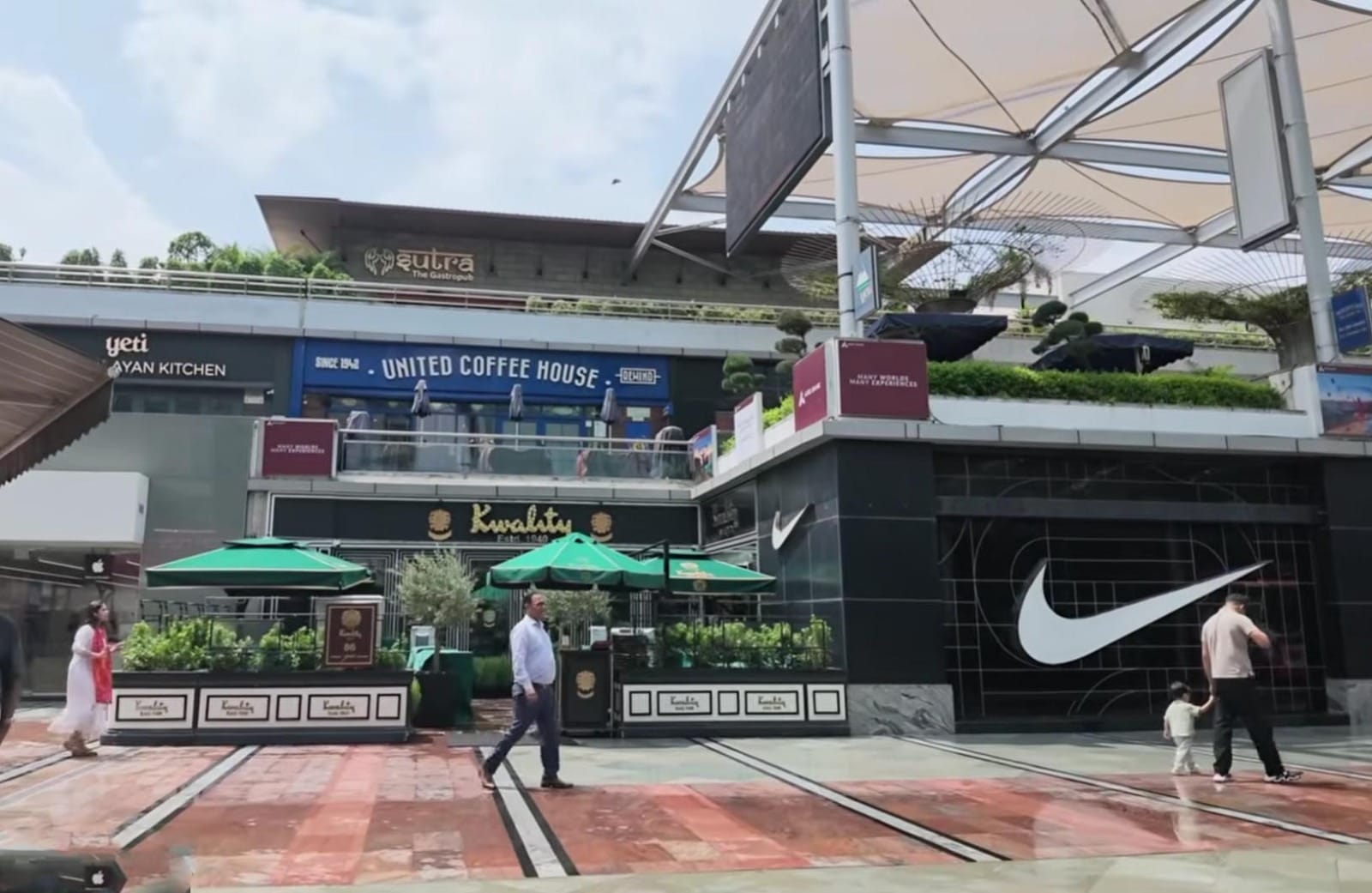 Kawasan Komersial dan Restoran Premium Gurugram Pemandangan eksterior kawasan komersial kelas atas dengan deretan restoran premium, kafe, dan etalase toko merek global yang berada di kawasan Gurugram