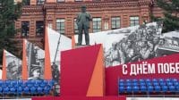 Patung monumen tokoh revolusioner Vladimir Lenin yang berdiri kokoh dengan dekorasi peringatan sejarah di belakangnya.