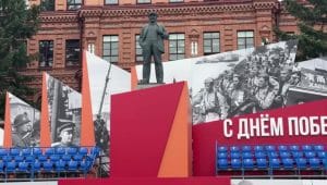 Patung monumen tokoh revolusioner Vladimir Lenin yang berdiri kokoh dengan dekorasi peringatan sejarah di belakangnya.