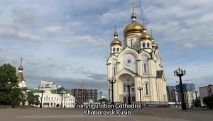 Gereja Transfiguration di Khabarovsk dengan kubah berbentuk bawang berlapis emas khas Ortodoks Rusia di bawah langit cerah.