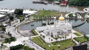 Pemandangan udara Masjid Omar Ali Saifuddien di Brunei Darussalam dengan kubah emas berkilau dan danau buatan yang tenang.