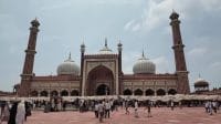 Kemegahan bangunan utama Jama Masjid Delhi peninggalan Shah Jahan dengan kubah marmer putih dan menara batu pasir merah yang dipadati lautan jamaah di halamannya.
