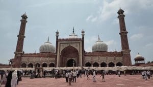 Kemegahan bangunan utama Jama Masjid Delhi peninggalan Shah Jahan dengan kubah marmer putih dan menara batu pasir merah yang dipadati lautan jamaah di halamannya.