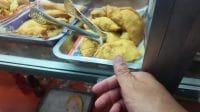Nampan etalase berisi aneka kudapan gorengan kekuningan di sebuah kedai.