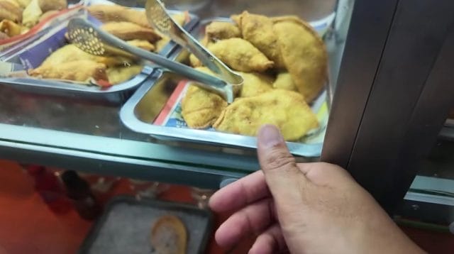 Nampan etalase berisi aneka kudapan gorengan kekuningan di sebuah kedai.