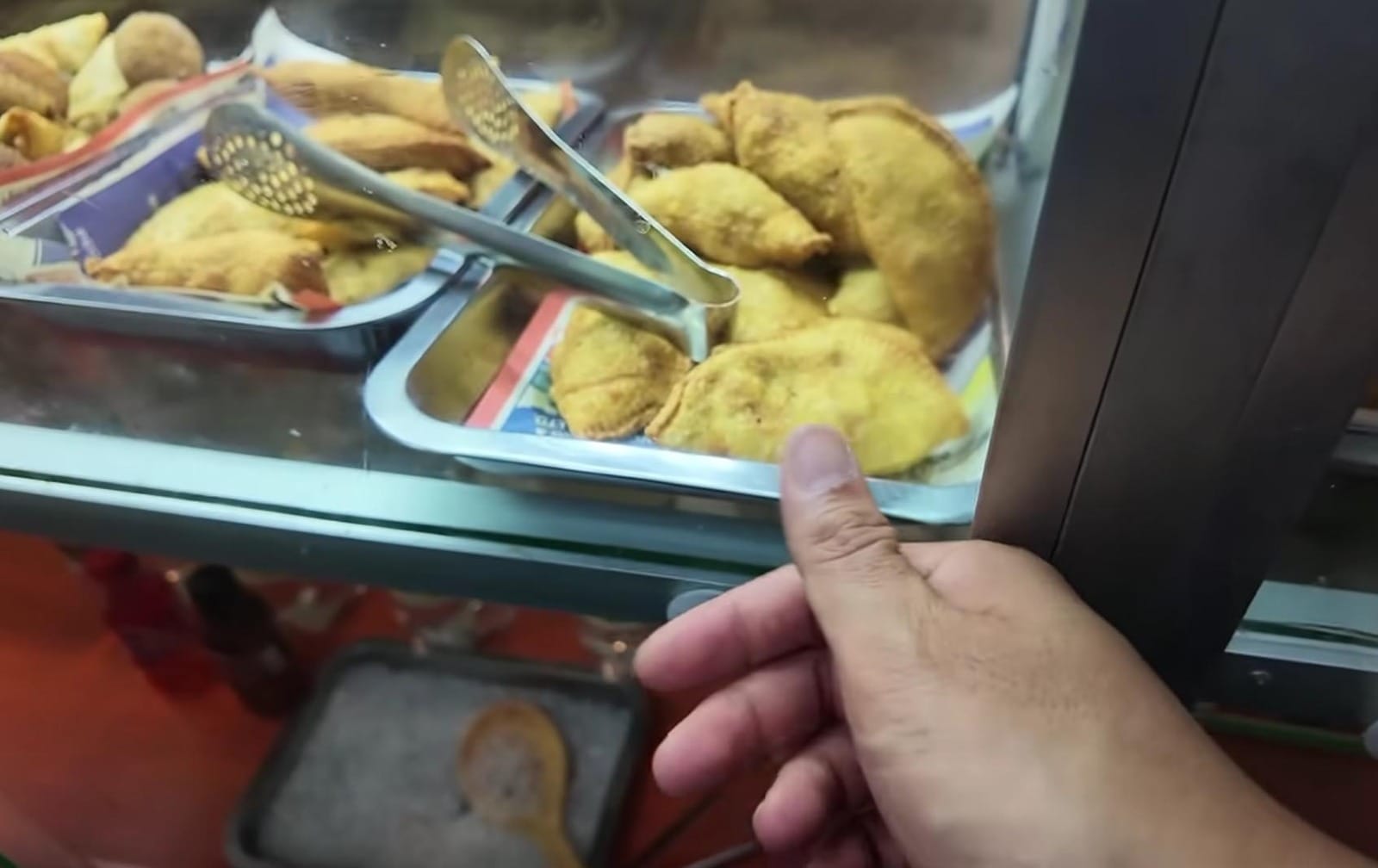 Nampan etalase berisi aneka kudapan gorengan kekuningan di sebuah kedai.