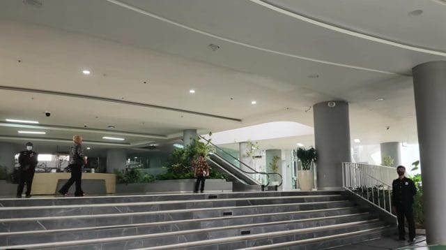 Petugas aparatur berseragam berdiri menjaga area lobi ruang pelayanan di dalam gedung perkantoran Otorita IKN