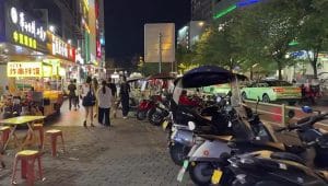 Suasana kehidupan malam di jalanan Xian dengan keramaian wisatawan, motor listrik, dan pedagang kaki lima.