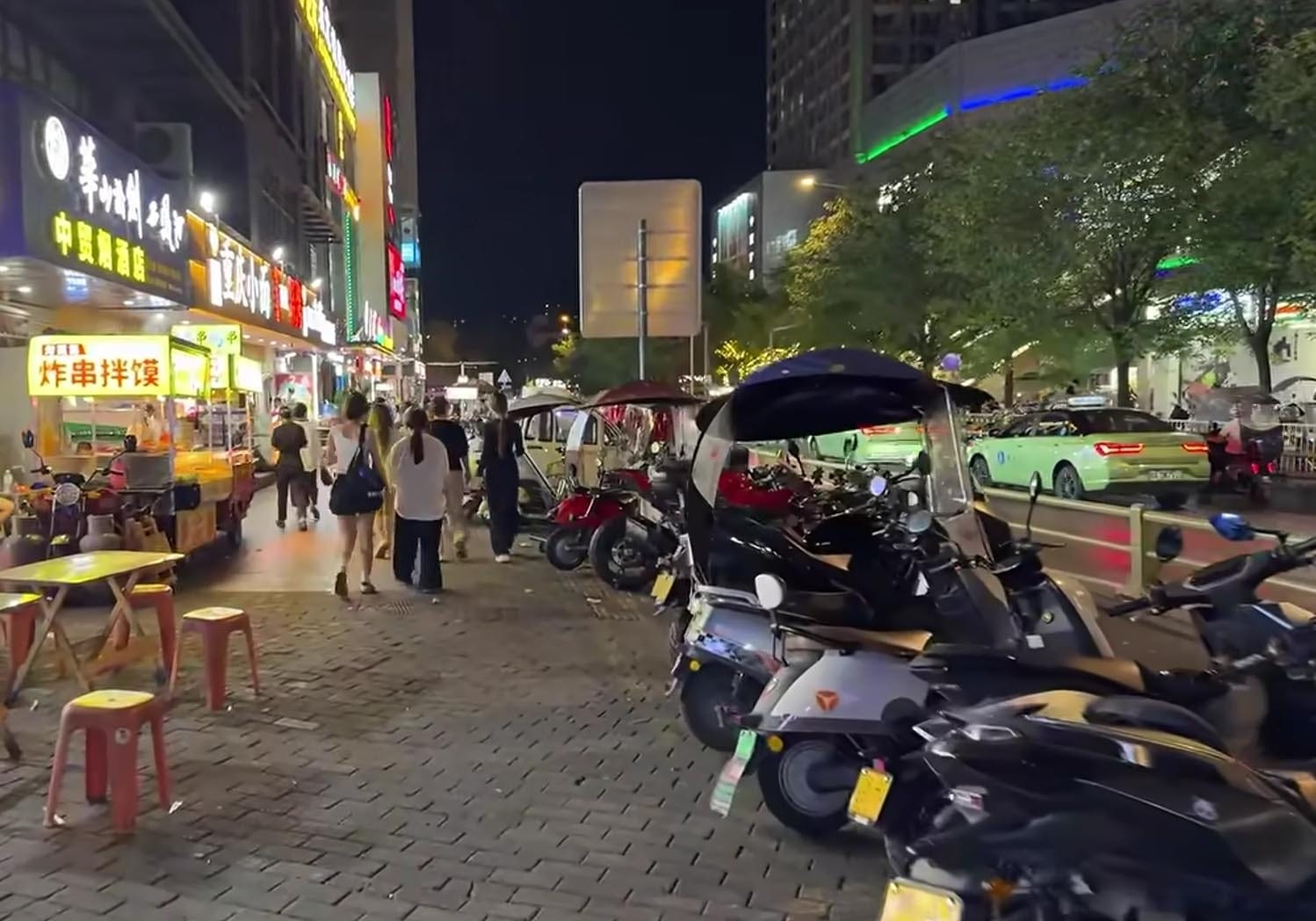 Suasana kehidupan malam di jalanan Xian dengan keramaian wisatawan, motor listrik, dan pedagang kaki lima.