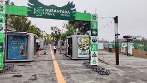 Papan gerbang hijau bertuliskan Nusantara Park di kawasan komersial modern dengan deretan tenant kontainer.