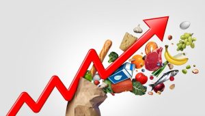Grafik panah merah naik berlatar belakang berbagai kebutuhan bahan pokok dan makanan.