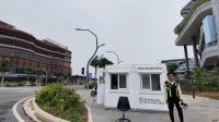 Petugas keamanan berpose di samping pos penjagaan modern bertuliskan Otorita Ibu Kota Nusantara.