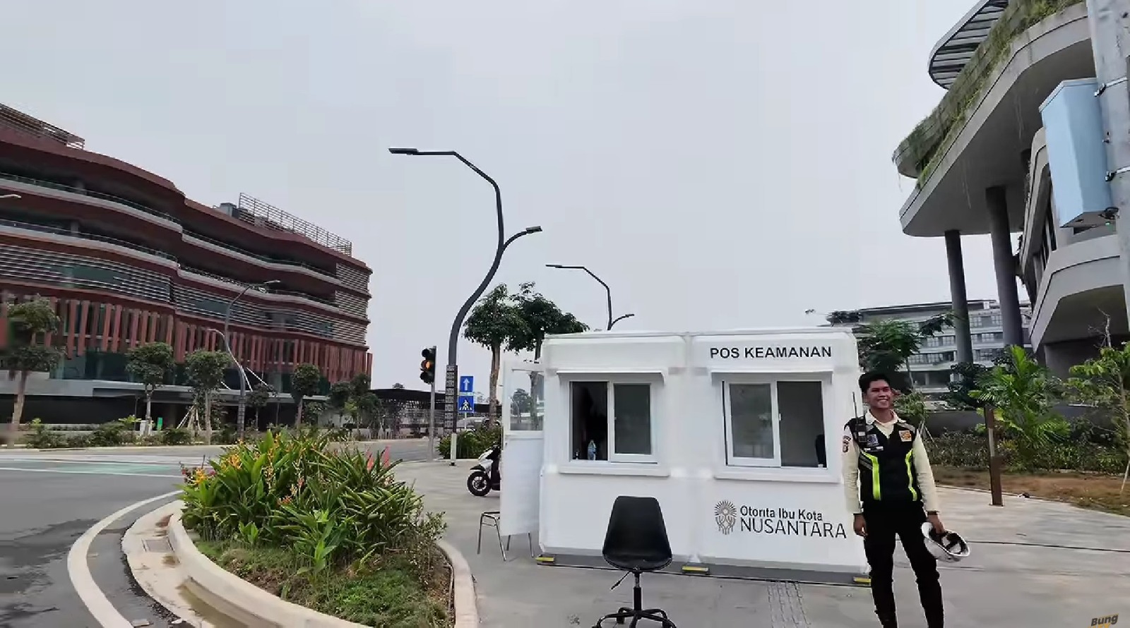 Petugas keamanan berpose di samping pos penjagaan modern bertuliskan Otorita Ibu Kota Nusantara.