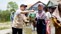 Petugas BAZNAS menyalurkan bantuan beras Zakat Fitrah kepada warga di daerah banjir.