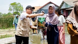 Petugas BAZNAS menyalurkan bantuan beras Zakat Fitrah kepada warga di daerah banjir.