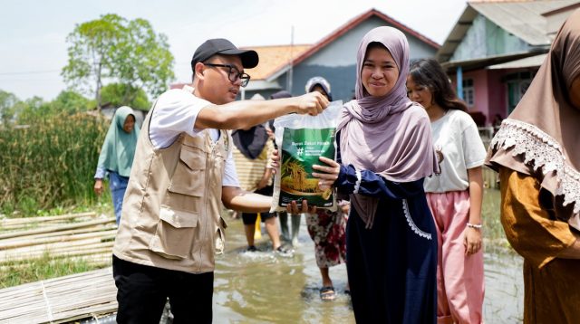 Petugas BAZNAS menyalurkan bantuan beras Zakat Fitrah kepada warga di daerah banjir.