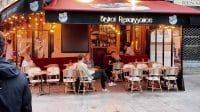 Suasana luar ruangan sebuah kafe kecil di Paris bernama Bistrot Renaissance dengan beberapa pelanggan duduk di kursi rotan.