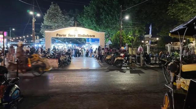 Gerbang masuk Pasar Sore Malioboro yang terang benderang oleh lampu di malam hari.