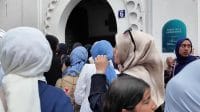 Kerumunan perempuan, beberapa di antaranya mengenakan jilbab, sedang berkumpul atau berjalan di luar ruangan.