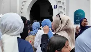 Kerumunan perempuan, beberapa di antaranya mengenakan jilbab, sedang berkumpul atau berjalan di luar ruangan.