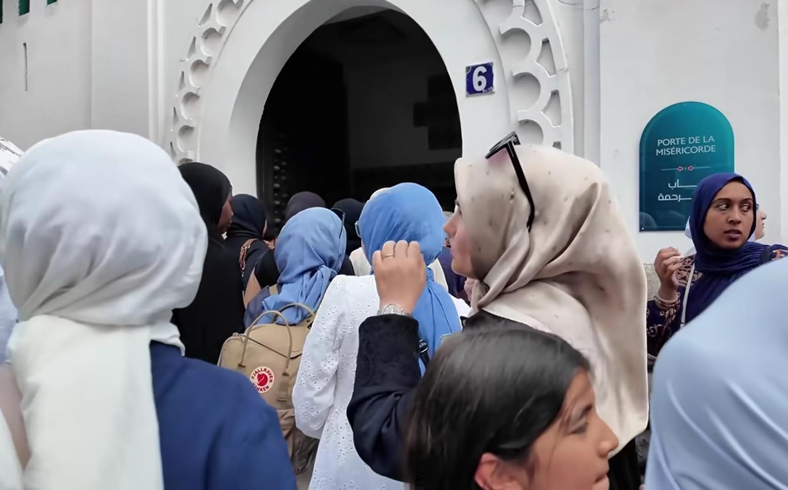 Kerumunan perempuan, beberapa di antaranya mengenakan jilbab, sedang berkumpul atau berjalan di luar ruangan.