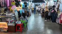 Pedagang perempuan dan pembeli sedang berinteraksi di lorong toko batik Pasar Beringharjo Yogyakarta.