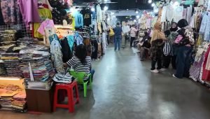 Pedagang perempuan dan pembeli sedang berinteraksi di lorong toko batik Pasar Beringharjo Yogyakarta.