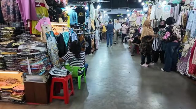 Pedagang perempuan dan pembeli sedang berinteraksi di lorong toko batik Pasar Beringharjo Yogyakarta.