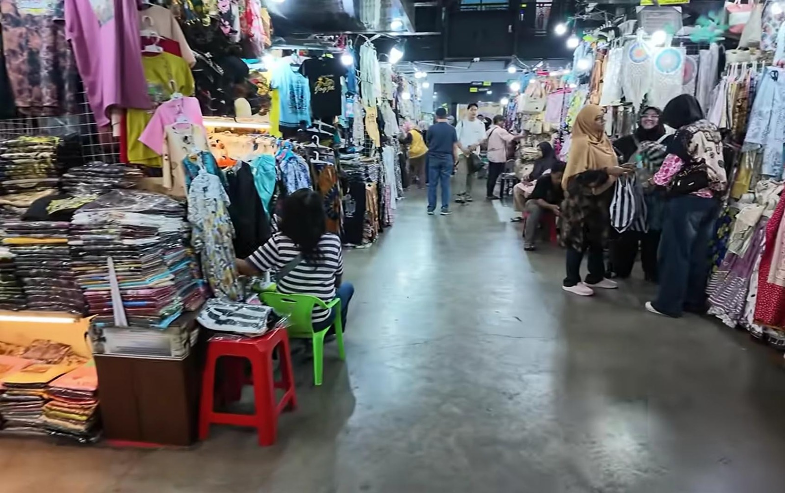 Pedagang perempuan dan pembeli sedang berinteraksi di lorong toko batik Pasar Beringharjo Yogyakarta.