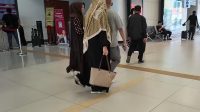 Dua penumpang perempuan berhijab berjalan di hall stasiun Whoosh membawa tas kerja.
