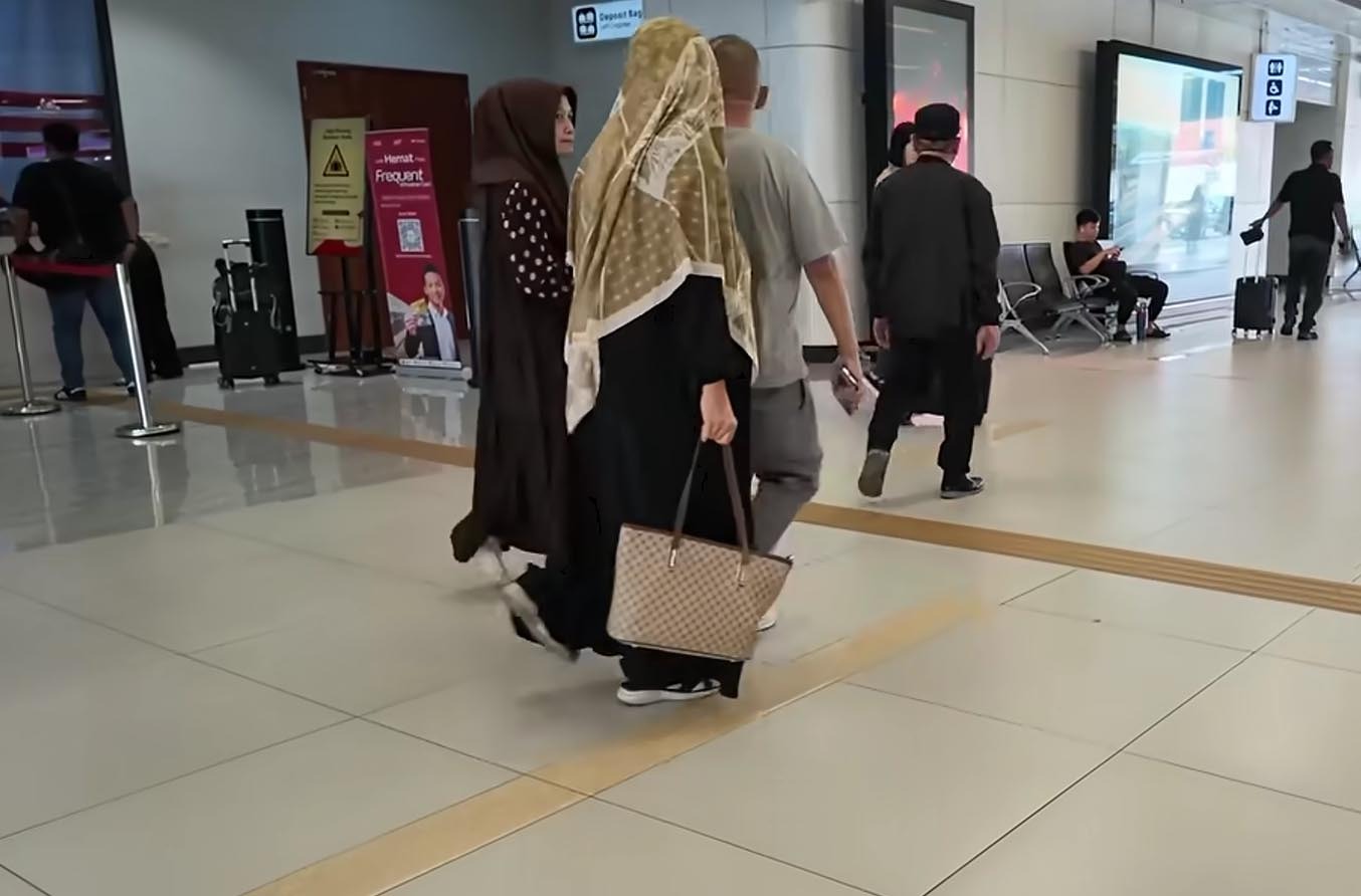 Dua penumpang perempuan berhijab berjalan di hall stasiun Whoosh membawa tas kerja.
